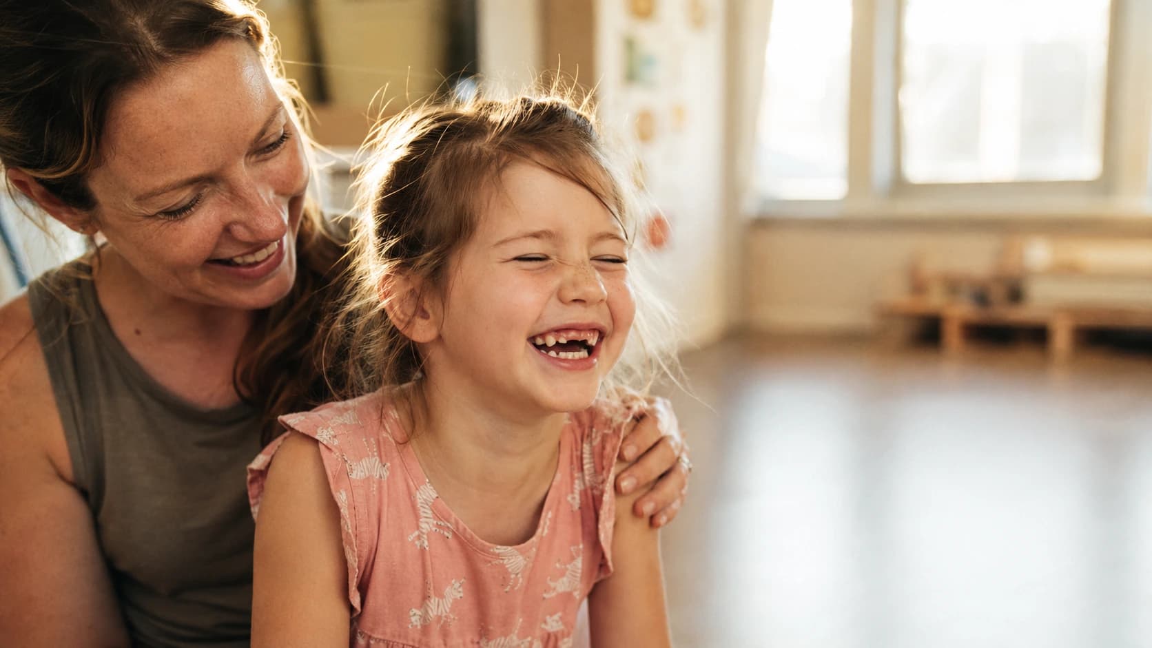 A parent and child laughing together at a kids' activity