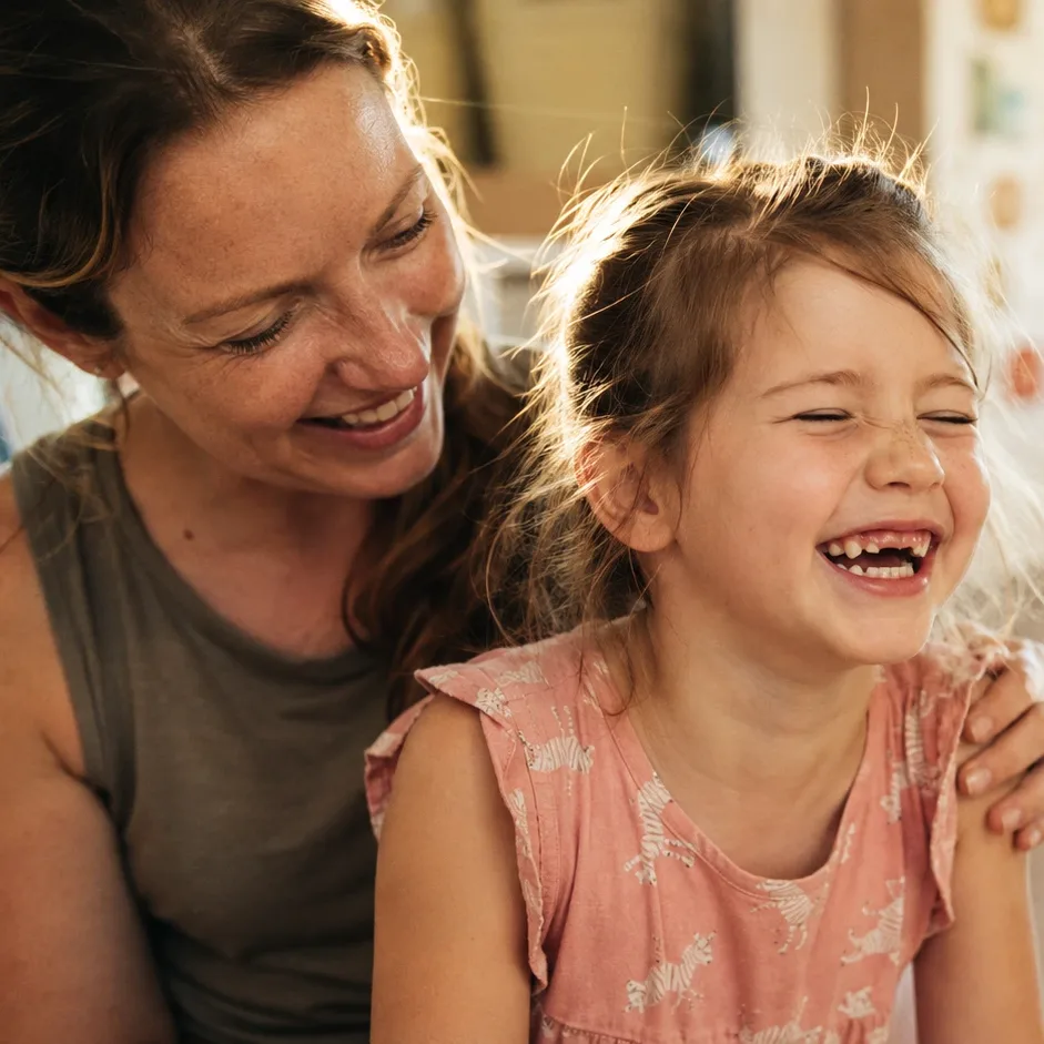 A mother laughing together with her daughter at an activity